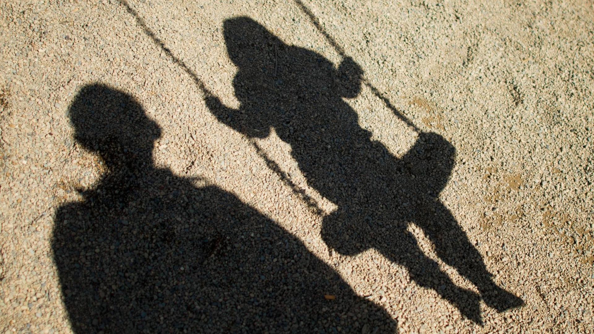 Der Schatten von einem Mann und einem schaukelnden Kind fallen auf den Sand auf einem Spielplatz in Braunschweig (Niedersachsen). Foto: Julian Stratenschulte/dpa +++(c) dpa - Bildfunk+++ Der Schatten von einem Mann und einem schaukelnden Kind fallen auf den Sand auf einem Spielplatz in Braunschweig (Niedersachsen). Foto: Julian Stratenschulte/dpa +++(c) dpa - Bildfunk+++