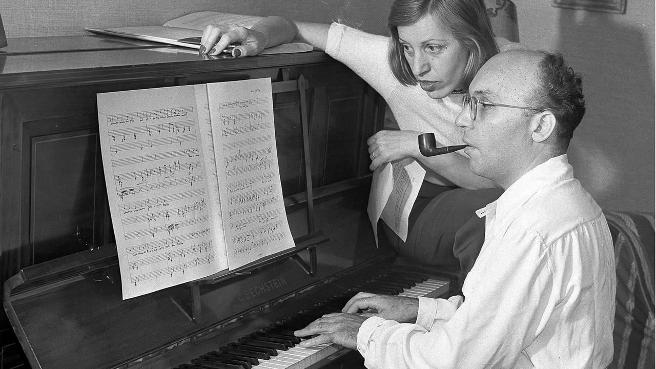 Der Komponist Kurt Weill und seine Frau, die Schauspielerin Lotte Lenya, am 17. August 1942 im US-Exil bei New York vor dem Klavier, wobei sie sich zu ihm und den Noten herunterbeugt.