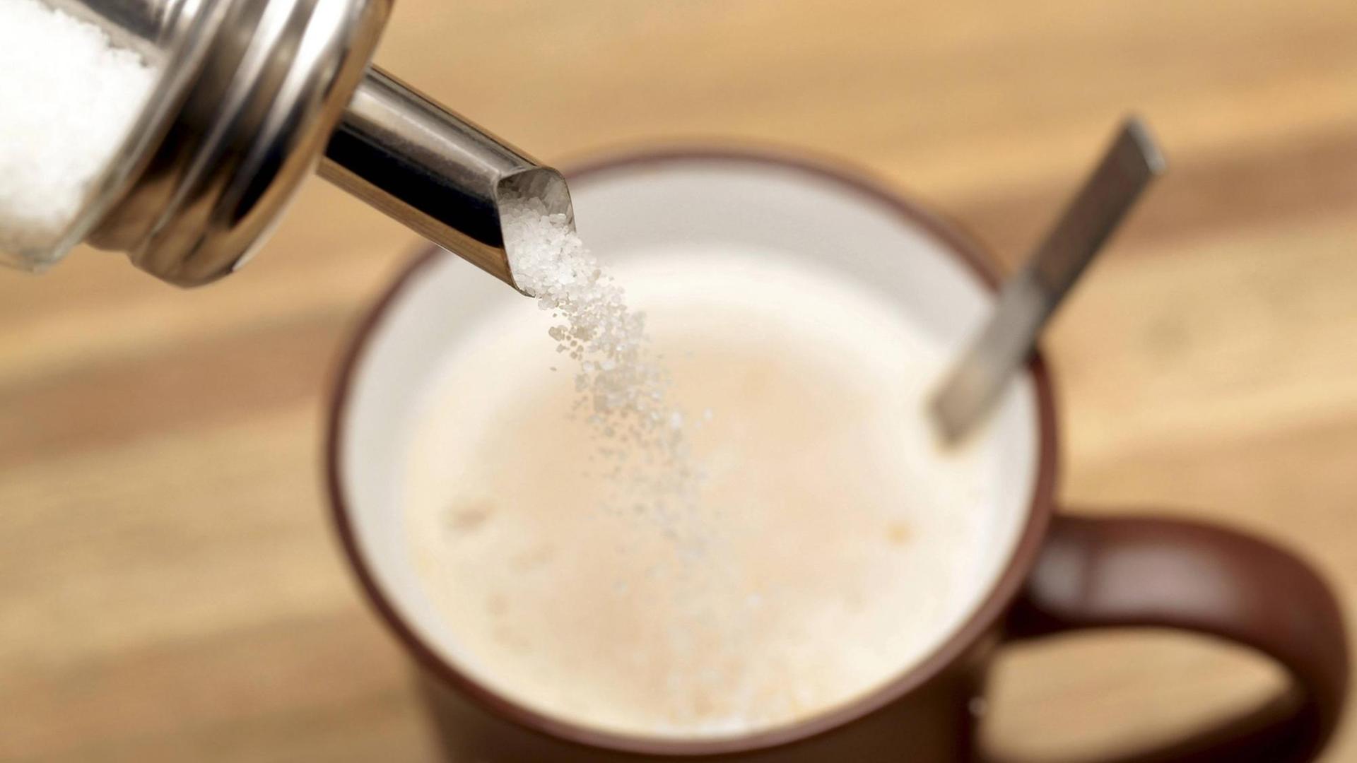 Ein Zuckerstreuer über eine Tasse Kaffee Ein Zuckerstreuer über eine Tasse Kaffee