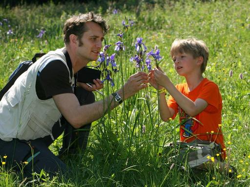 Auf einer Wiese bei Crawinkel (Ilm-Kreis) betrachten der Biologe Andreas Weber und der 7-jährige Max am Samstag (09.06.2007) eine wild gewachsene Sibirische Schwertlilie (Iris sibirica).