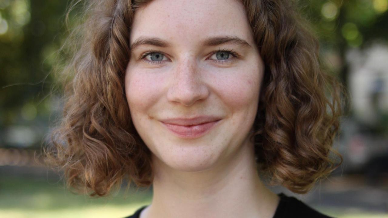Pauline Pieper steht in einem Park, im Hintergrund in der Unschärfe sind Bäume zu sehen, und schaut lächelt in die Kamera. Pauline Pieper steht in einem Park, im Hintergrund in der Unschärfe sind Bäume zu sehen, und schaut lächelt in die Kamera.