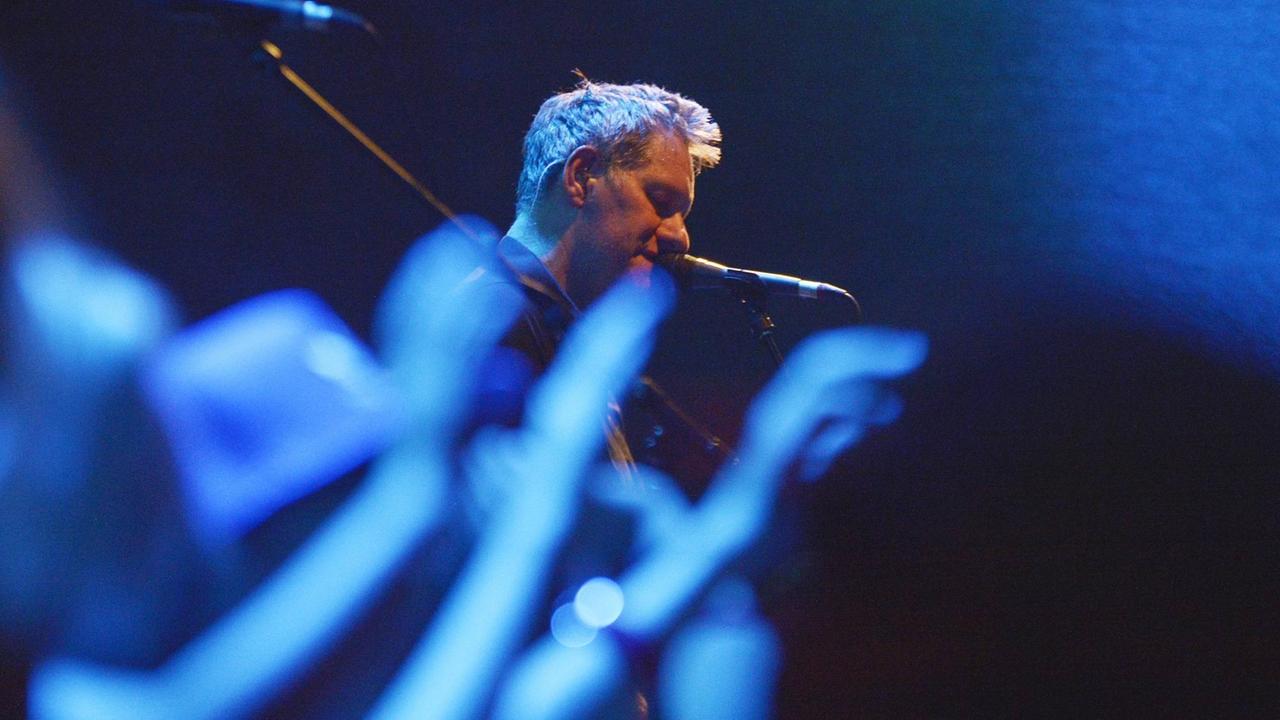 Markus Wiebusch steht auf der Bühne und singt ins Mikrofon. Im Vordergrund sind die Arme des klatschenden Publikums zu sehen. Markus Wiebusch steht auf der Bühne und singt ins Mikrofon. Im Vordergrund sind die Arme des klatschenden Publikums zu sehen.