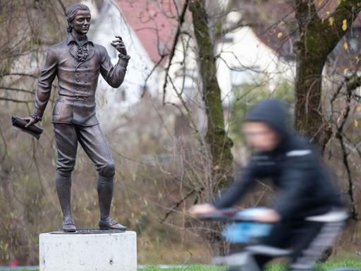 Ein Fahrradfahrer passiert die Skulptur von Friedrich Hölderlin in Nürtingen.