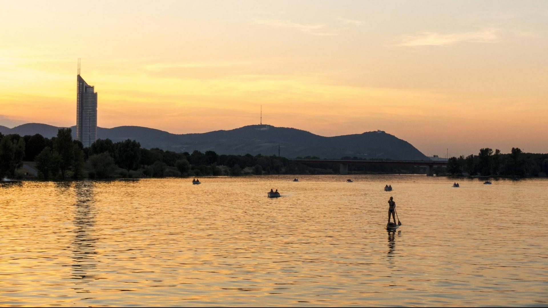 Ein Mann steht auf einem Paddling-Board auf der Donau bei Wien. Ein Mann steht auf einem Paddling-Board auf der Donau bei Wien.