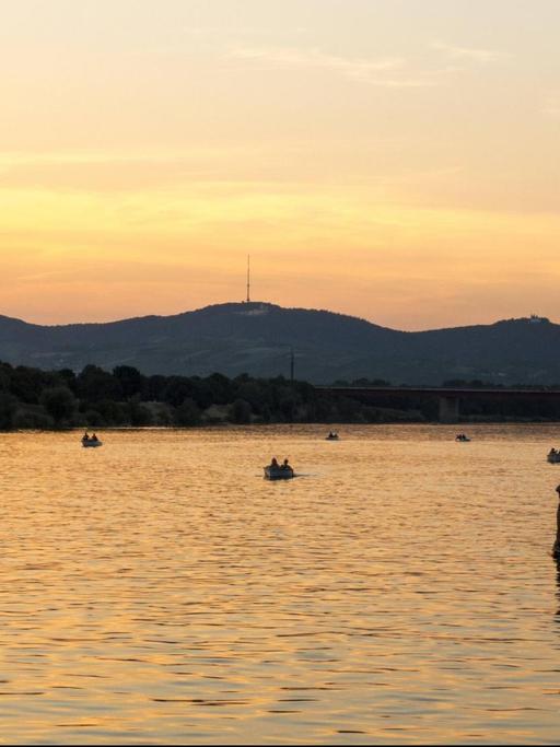Ein Mann steht auf einem Paddling-Board auf der Donau bei Wien.