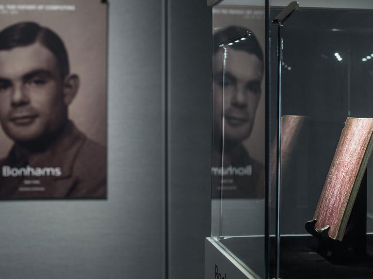 In einer Vitrine werden am 19.3.2015 in Hongkong handschriftliche Notizen von Alan Turin (1912-1954) ausgestellt, im Hintergrund ein Plakat mit einem Foto des britischen Mathematikers.