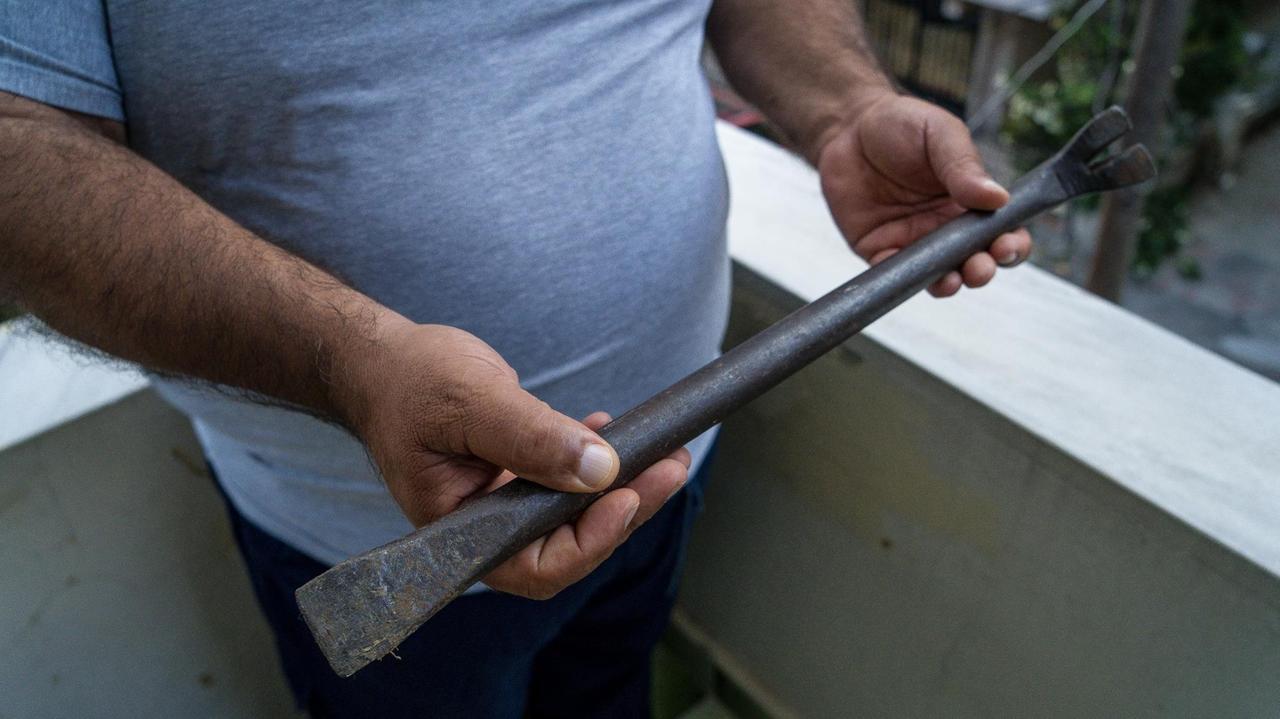 Ein Mann hält ein langes Metallteil in beiden Händen. Ein Mann hält ein langes Metallteil in beiden Händen.