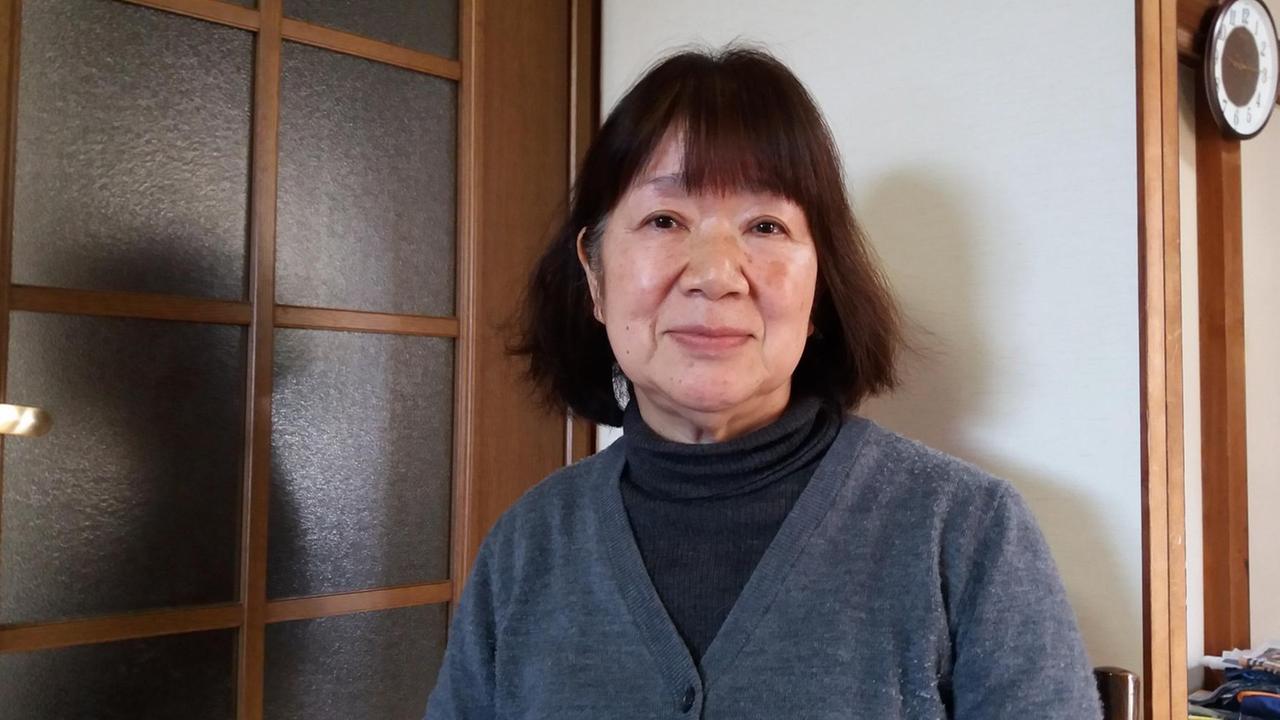 Haruko Kasugaya in ihrer Wohnung. Sie lächelt in die Kamera. Haruko Kasugaya in ihrer Wohnung. Sie lächelt in die Kamera.