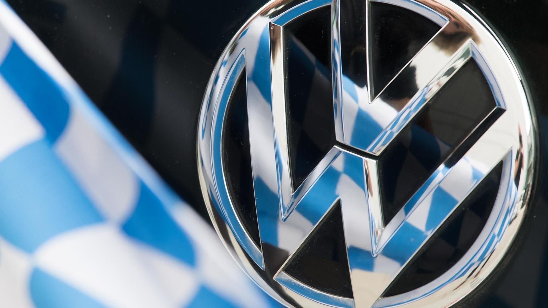 ILLUSTRATION - Ein weiß-blaues Rautenmuster spiegelt sich am 02.08.2016 in München (Bayern) im Logo eines VW-Emblems an einem PKW. Bayern wird Volkswagen wegen der Folgen des Diesel-Skandals auf Schadenersatz verklagen. Foto: Peter Kneffel/dpa (zu dpa "Bayern verklagt Volkswagen wegen Folgen des Diesel-Skandals" vom 02.08.2016) | Verwendung weltweit ILLUSTRATION - Ein weiß-blaues Rautenmuster spiegelt sich am 02.08.2016 in München (Bayern) im Logo eines VW-Emblems an einem PKW. Bayern wird Volkswagen wegen der Folgen des Diesel-Skandals auf Schadenersatz verklagen. Foto: Peter Kneffel/dpa (zu dpa "Bayern verklagt Volkswagen wegen Folgen des Diesel-Skandals" vom 02.08.2016) | Verwendung weltweit