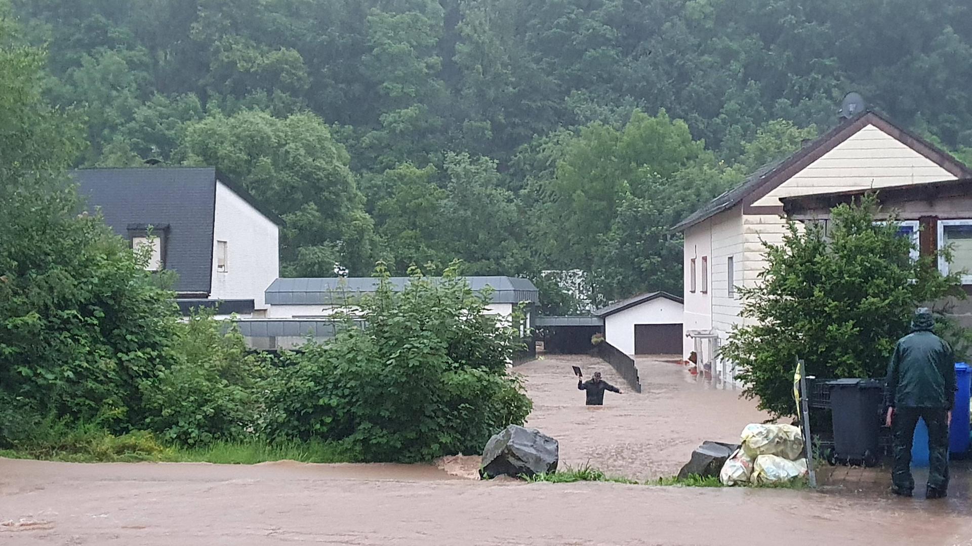 Ein Mann watet durch das Wasser auf einer Straße in Prüm/Eifel am 15.07.2021.