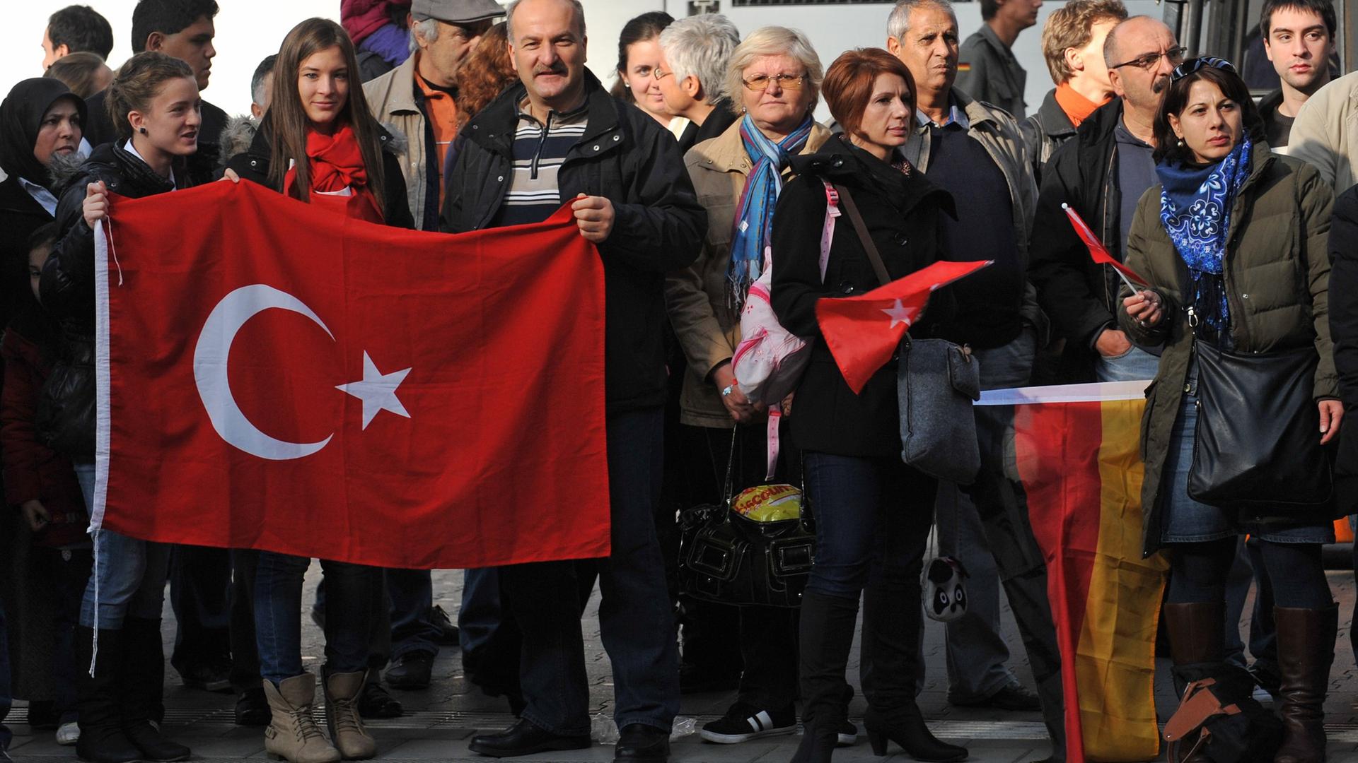 Menschen mit türkischen und deutschen Flaggen warten im Hauptbahnhof in München auf die Ankunft des Erinnerungszuges "50 Jahre Migration". Menschen mit türkischen und deutschen Flaggen warten im Hauptbahnhof in München auf die Ankunft des Erinnerungszuges "50 Jahre Migration".
