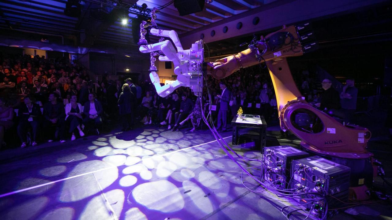 Ein Roboterarm in einer farbigen Lichtatmosphäre auf der Gala des "Ars Electronica"-Festivals