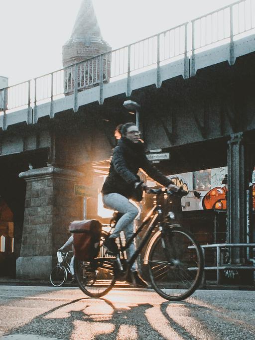 Eine Radfahrerin fährt in Berlin dei Oberbaumbrücke entlang.