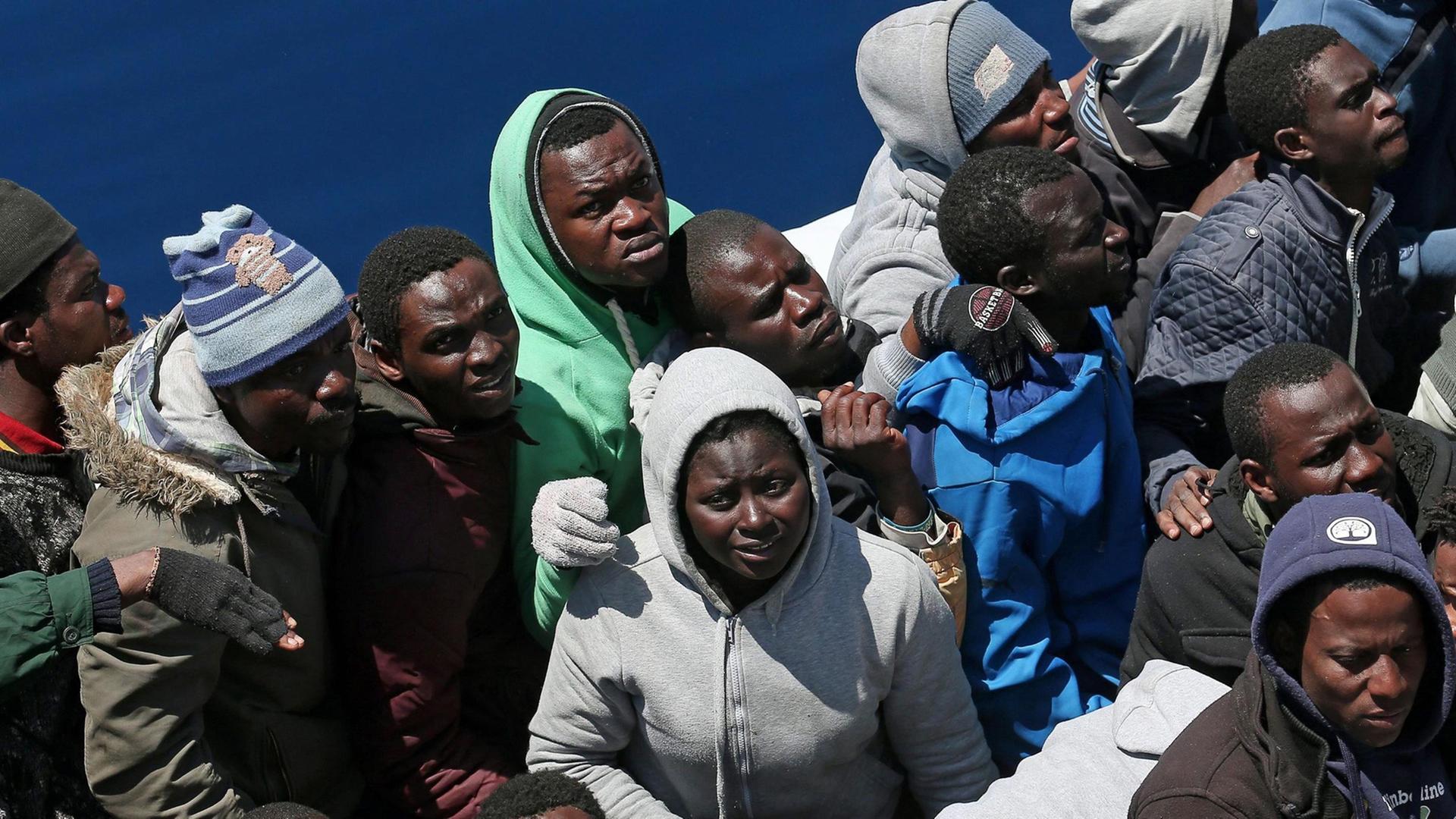 Ein Dutzend Flüchtlinge drängen sich auf einem kleinen Boot im Mittelmeer, bevor sie auf das Schiff der Küstenwache gelangen können. Ein Dutzend Flüchtlinge drängen sich auf einem kleinen Boot im Mittelmeer, bevor sie auf das Schiff der Küstenwache gelangen können.