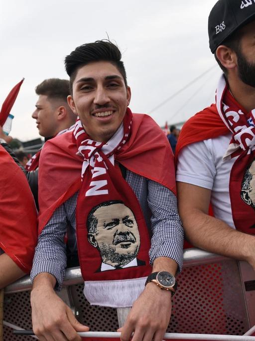 Anhänger des türkischen Staatspräsidenten Erdogan tragen bei der Kundgebung Schals mit dem Bild des türkischen Präsidenten.