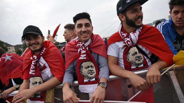 Anhänger des türkischen Staatspräsidenten Erdogan tragen bei der Kundgebung Schals mit dem Bild des türkischen Präsidenten.