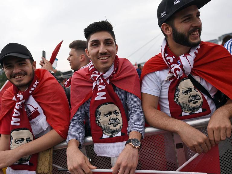 Anhänger des türkischen Staatspräsidenten Erdogan tragen bei der Kundgebung Schals mit dem Bild des türkischen Präsidenten.