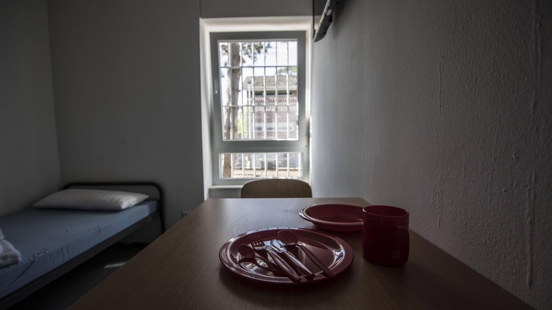 Ein Zimmer in einem Abschiebegefängnis mit einem Tisch und einem Bett vor einem vergitterten Fenster. Ein Zimmer in einem Abschiebegefängnis mit einem Tisch und einem Bett vor einem vergitterten Fenster.