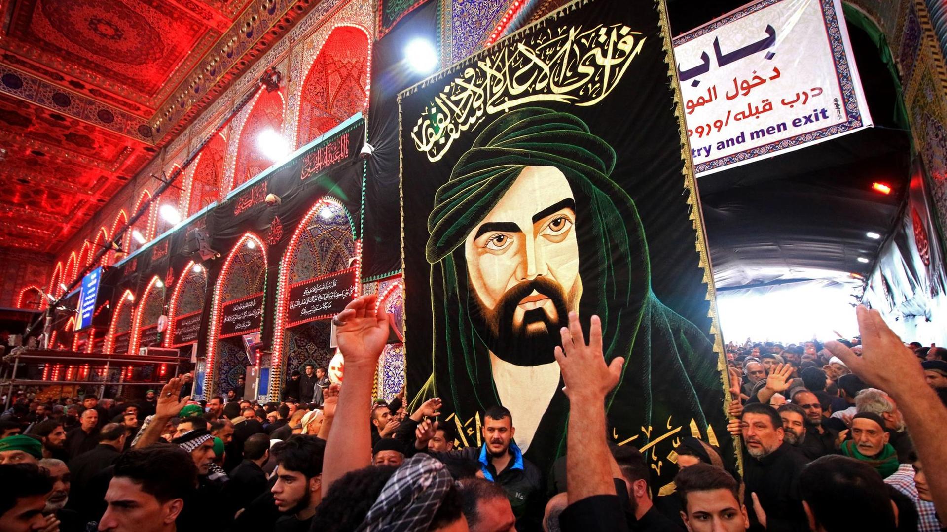 Schiitische Pilger beten im November 2017 in Kerbela (Irak) - Sie tragen ein Bild des Imam Hussein, eines Enkels Mohammeds, der im 7. Jahrhundert in Kerbela getötet wurde Schiitische Pilger beten im November 2017 in Kerbela (Irak) - Sie tragen ein Bild des Imam Hussein, eines Enkels Mohammeds, der im 7. Jahrhundert in Kerbela getötet wurde