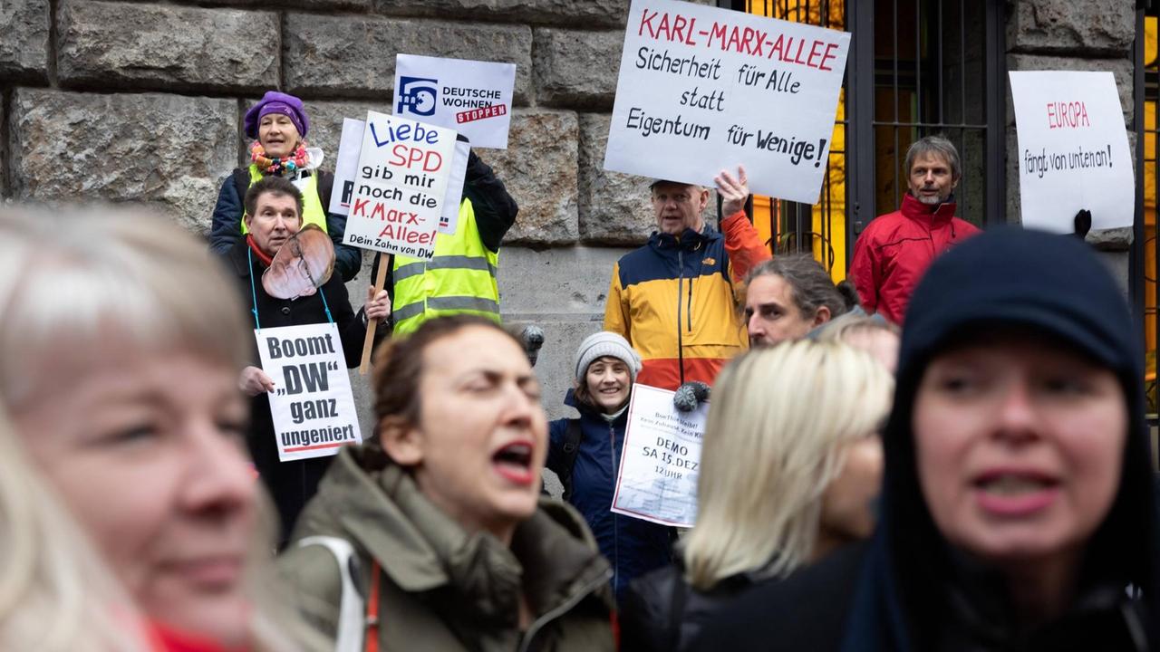 Menschen rufen Parolen und halten Protest-Plakate gegen den Verkauf der Gebäude in der Berliner Karl-Marx-Allee hoch. Menschen rufen Parolen und halten Protest-Plakate gegen den Verkauf der Gebäude in der Berliner Karl-Marx-Allee hoch.