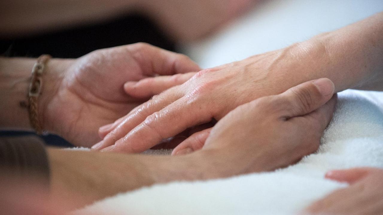 Die Hände eines sterben Menschen werden von einem Angehörigen gestreichelt. Die Hände eines sterben Menschen werden von einem Angehörigen gestreichelt.
