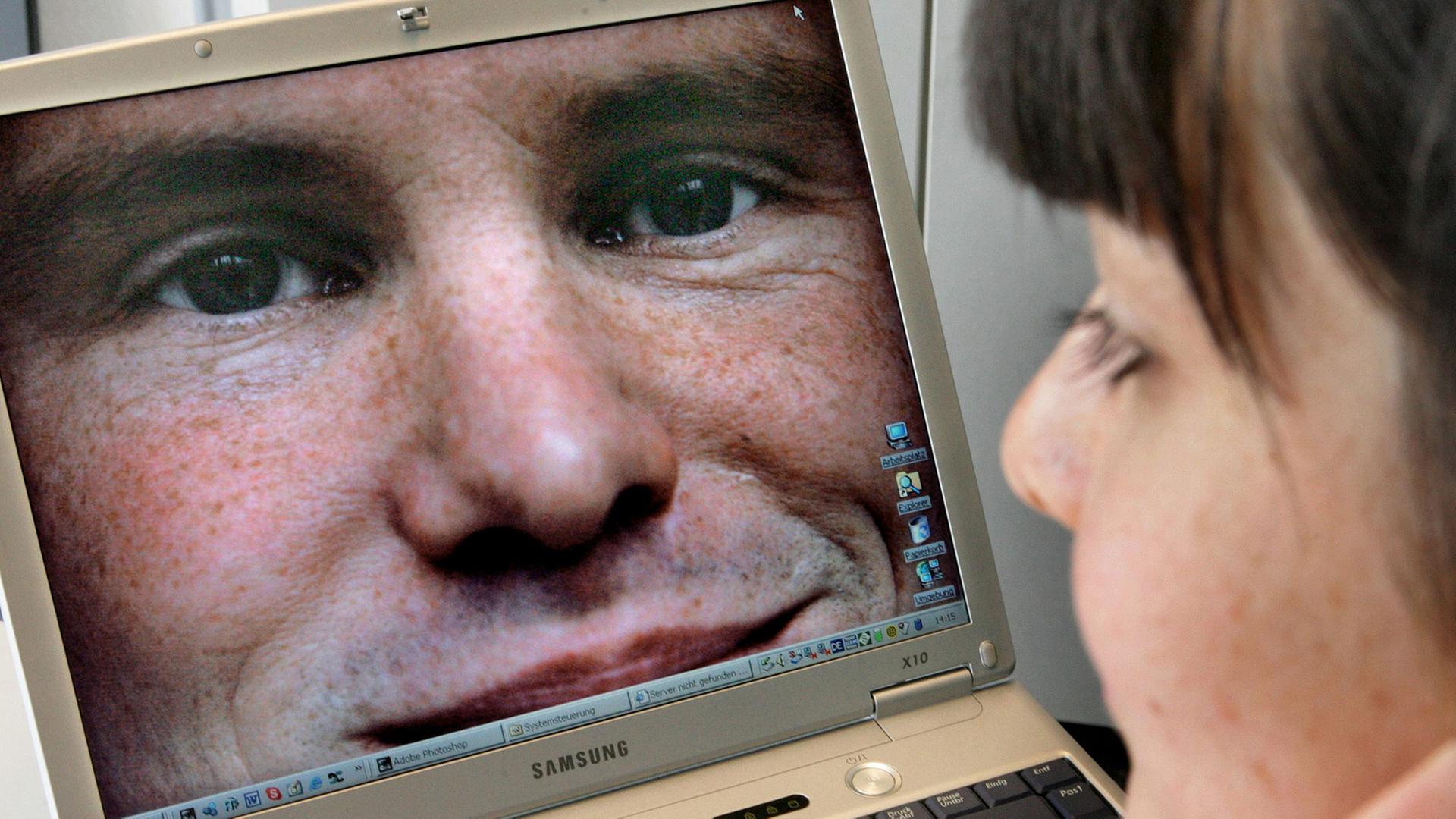 Das Bild eines jungen Mannes sieht sich diese Frau auf einem Laptop an. Das Bild eines jungen Mannes sieht sich diese Frau auf einem Laptop an.