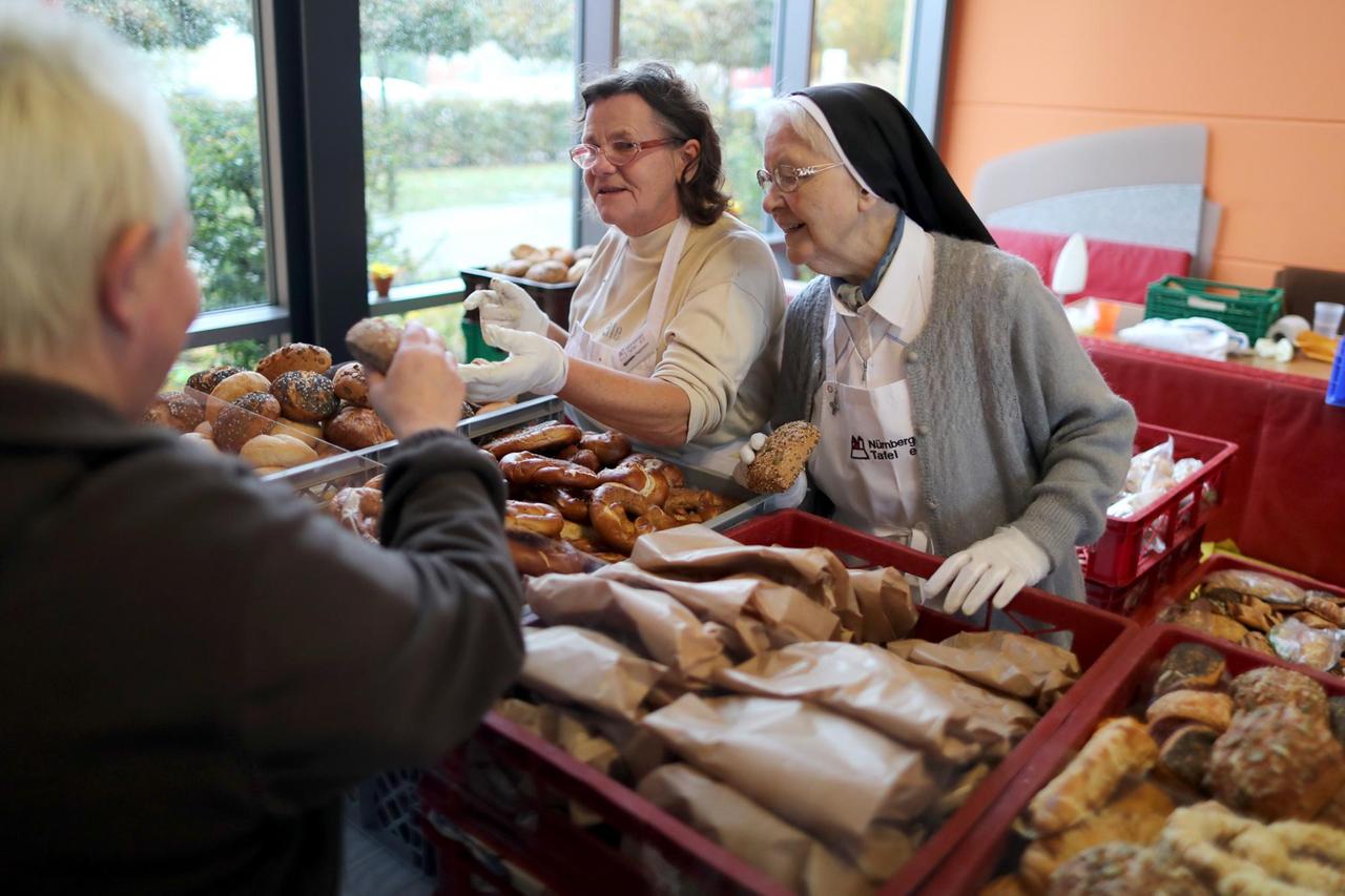 Ehrenamtliche Mitarbeiter der Nürnberger Tafel verteilen Lebensmittel. Nach kurzer Schließung hat die Nürnberger Tafel am 20.10. wieder eine Ausgabestelle geöffnet. Foto: Daniel Karmann/dpa | Verwendung weltweit Ehrenamtliche Mitarbeiter der Nürnberger Tafel verteilen Lebensmittel. Nach kurzer Schließung hat die Nürnberger Tafel am 20.10. wieder eine Ausgabestelle geöffnet. Foto: Daniel Karmann/dpa | Verwendung weltweit