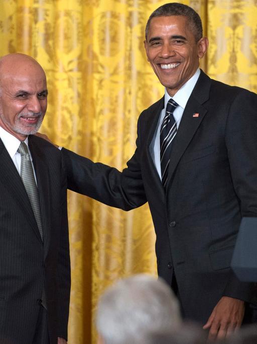 Im Pressekonferenzraum des Weißen Hauses: US-Präsident Obama und sein afghanischer Kollege Ghani lächeln in die Kameras, Obama hat seine Hand auf der Schulter Ghanis. 