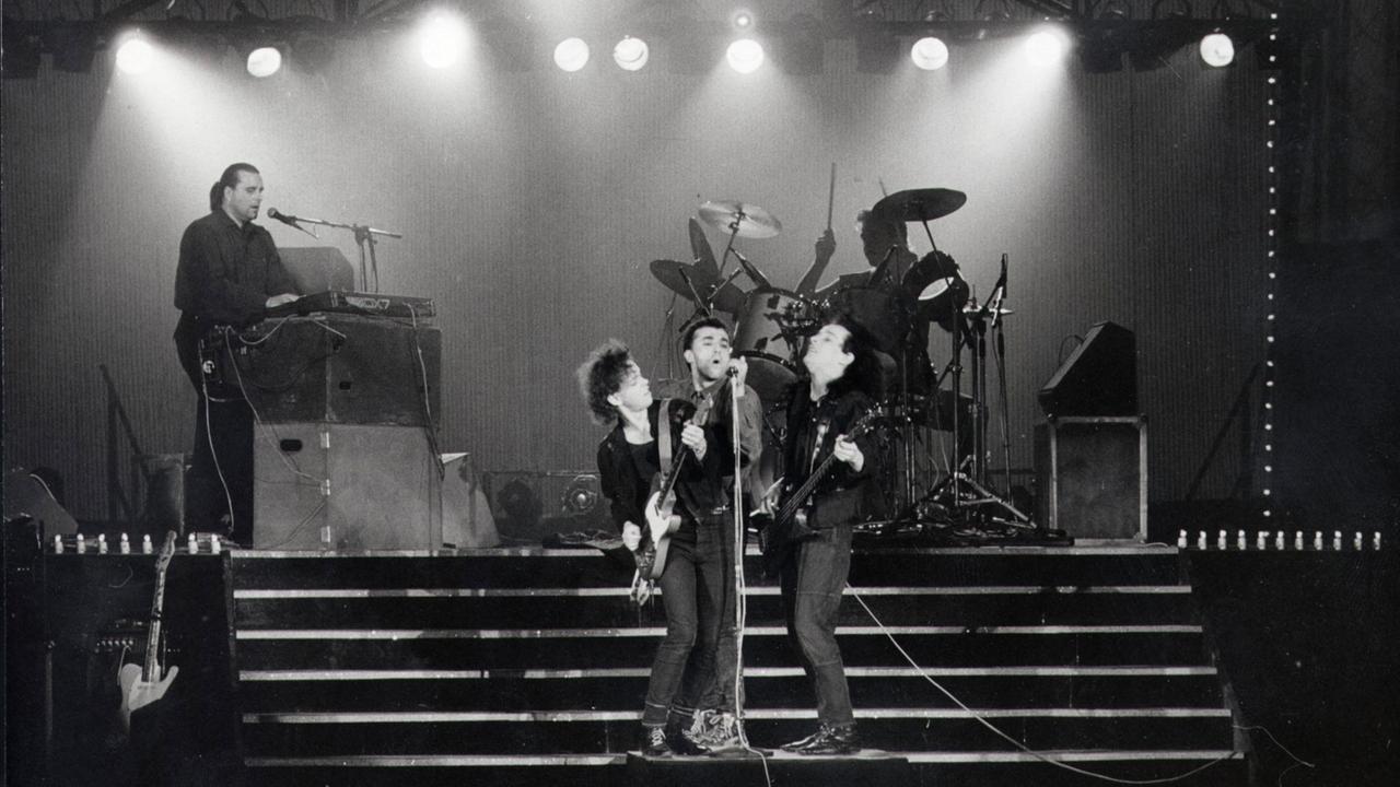 Schwarz-Weiß-Aufnahme eines Konzerts der Rockband Pankow am 15.3.1988 im Berliner Friedrichstadtpalast. Auf der Bühne stehen Sänger, Gitarrist und Bassist gemeinsam vor einem Mikrofon, im Hintergrund der Keyboarder und der Bassist.
