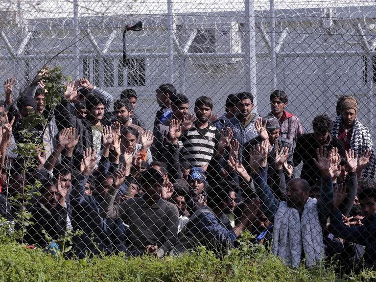 Menschen hinter einem Maschendrahtzaun auf der griechischen Insel Lesbos.