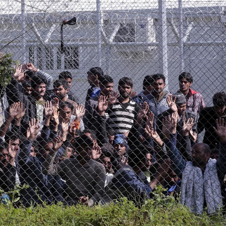Menschen hinter einem Maschendrahtzaun auf der griechischen Insel Lesbos.