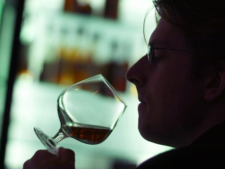 Ein Mann riecht an einem Glas Cognac in einer Hotelbar in München.