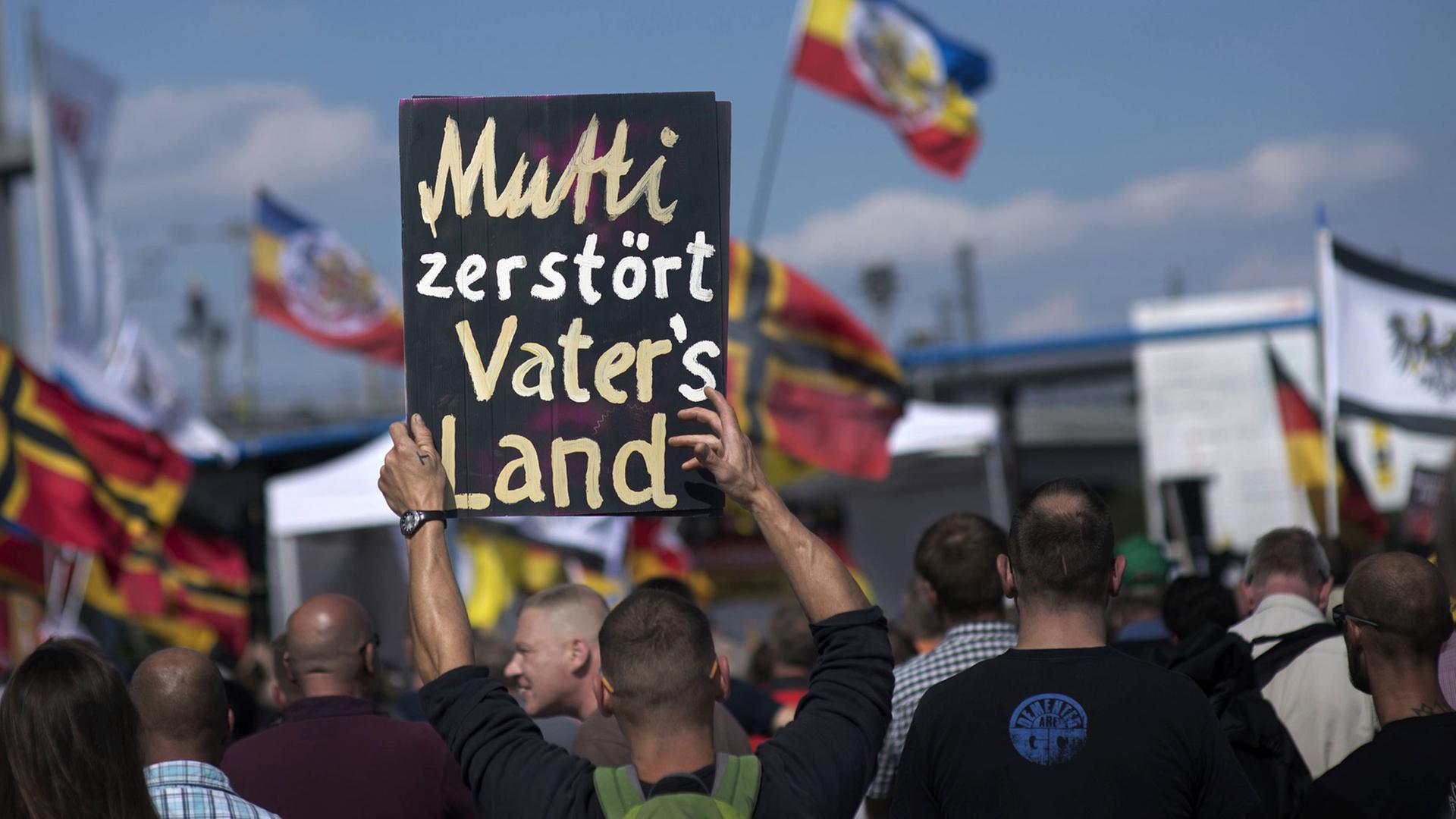 Auf einer Demonstration rechter Gruppen in Berlin am 30. Juli 2016 hält ein Demonstrant ein Plakat mit der Aufschrift "Mutti zerstoert Vaters Land" hoch. Unter den Teilnehmerm sind viele Neonazis, Mitglieder vom HoGeSa, NPD und Teilnehmer der Baergida und von Pegida, Patriotische Europaeer Gegen die Islamisierung des Abendlandes. Auf einer Demonstration rechter Gruppen in Berlin am 30. Juli 2016 hält ein Demonstrant ein Plakat mit der Aufschrift "Mutti zerstoert Vaters Land" hoch. Unter den Teilnehmerm sind viele Neonazis, Mitglieder vom HoGeSa, NPD und Teilnehmer der Baergida und von Pegida, Patriotische Europaeer Gegen die Islamisierung des Abendlandes.