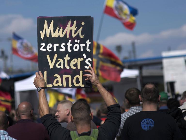 Auf einer Demonstration rechter Gruppen in Berlin am 30. Juli 2016 hält ein Demonstrant ein Plakat mit der Aufschrift "Mutti zerstoert Vaters Land" hoch.