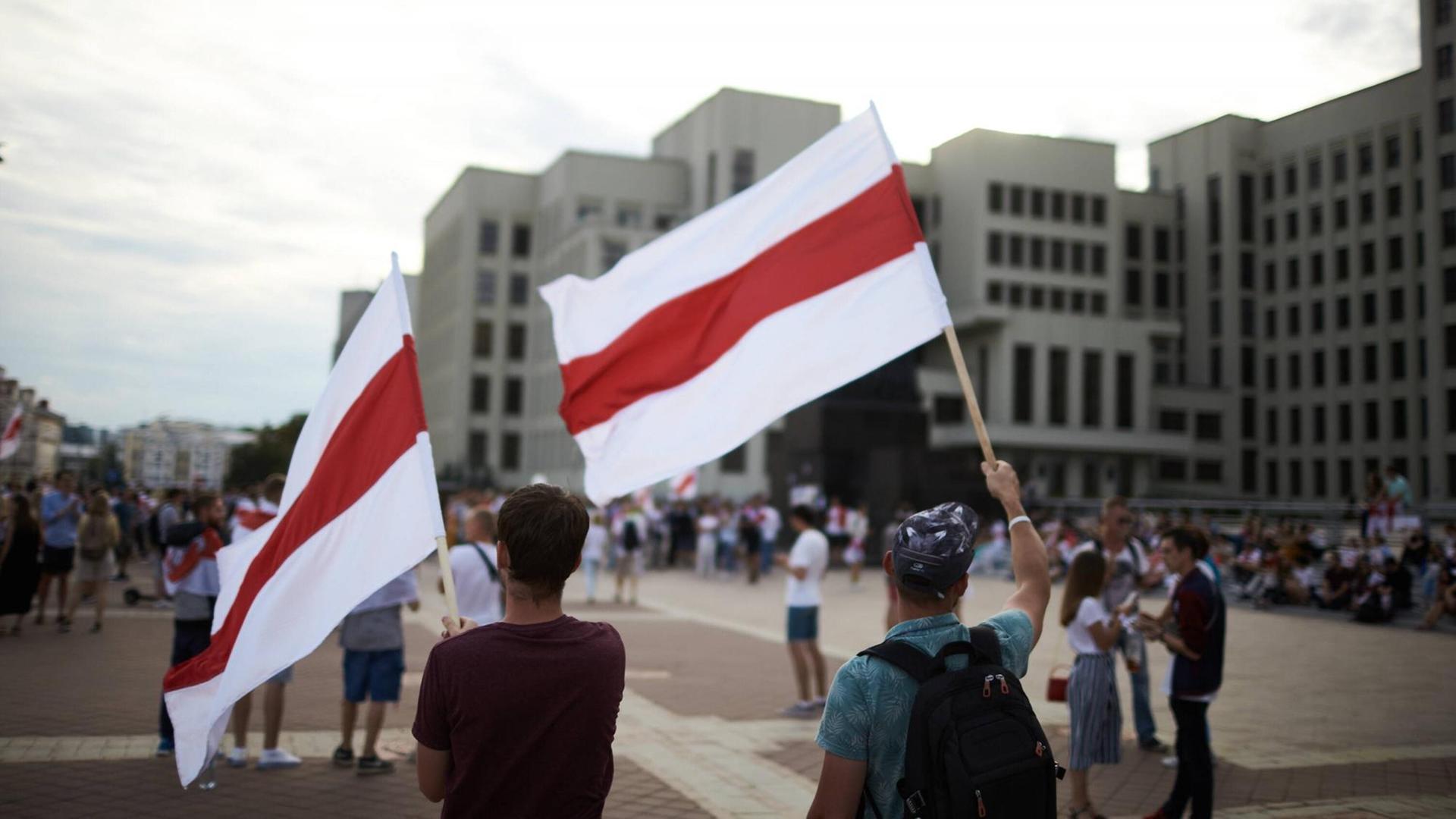 Demonstranten stehen mit weiß-rot-weißen Flaggen auf einem Platz in Minsk Demonstranten stehen mit weiß-rot-weißen Flaggen auf einem Platz in Minsk