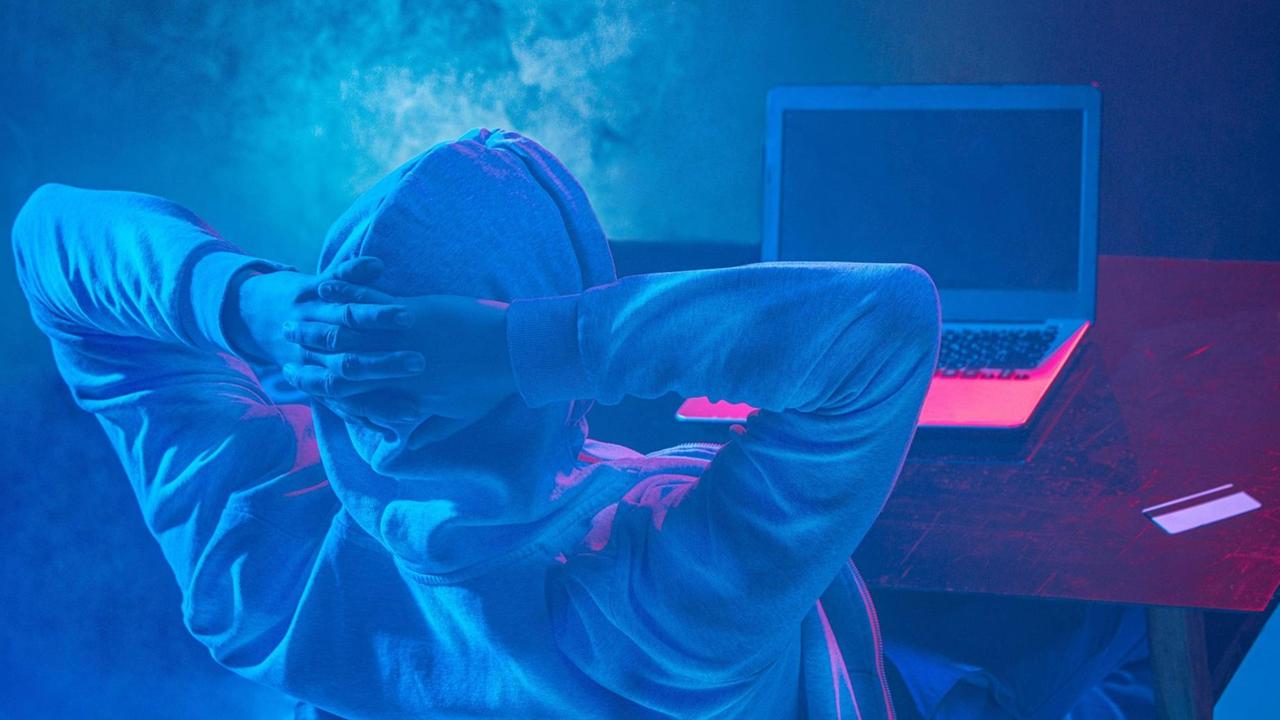 Ein Mensch im Kapuzenpulli sitzt vor einem Computerbildschirm. Ein Mensch im Kapuzenpulli sitzt vor einem Computerbildschirm.
