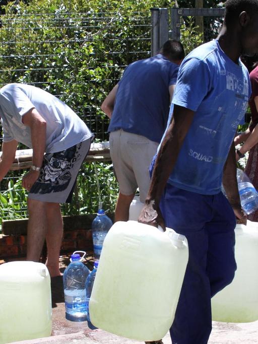 Menschen in Kapstadt füllen Wasserkanister an einer Quelle auf