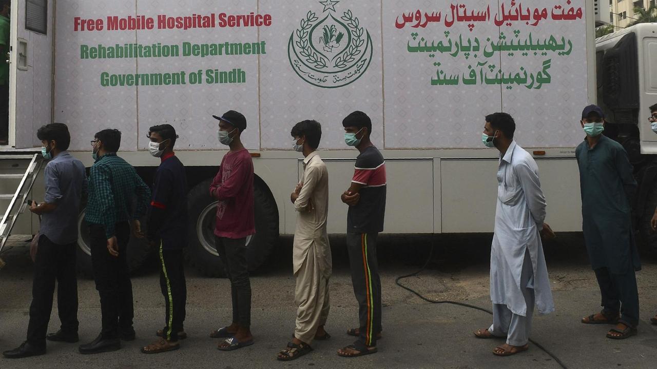In der pakistanischen Millionenstadt Karatschi stehen Hafenarbeiter für eine Impfung gegen das Coronavirus an. Es handelt sich um eine mobile Impfstation der Provinzregierung Sindh. In der pakistanischen Millionenstadt Karatschi stehen Hafenarbeiter für eine Impfung gegen das Coronavirus an. Es handelt sich um eine mobile Impfstation der Provinzregierung Sindh.