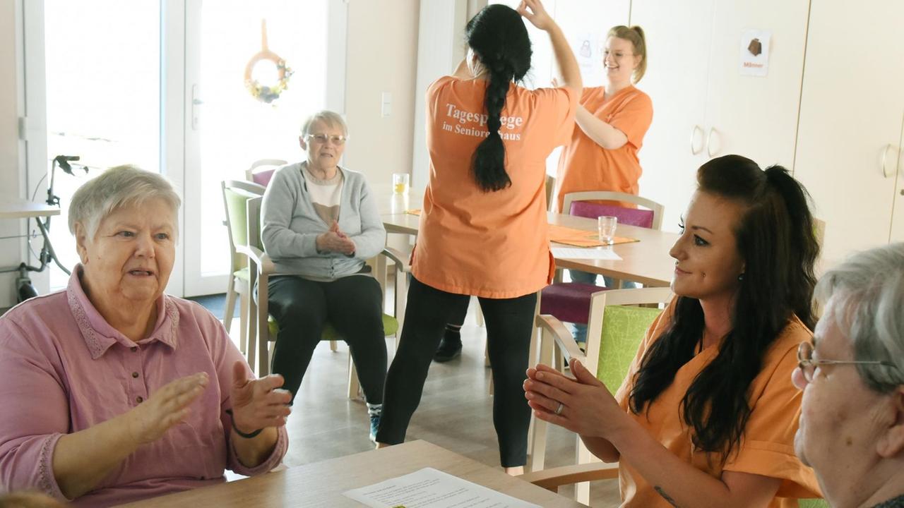 In einem Pflege-Heim ist eine Alten-Pflegerin mit Heim-Bewohnerinnen zu sehen. In einem Pflege-Heim ist eine Alten-Pflegerin mit Heim-Bewohnerinnen zu sehen.