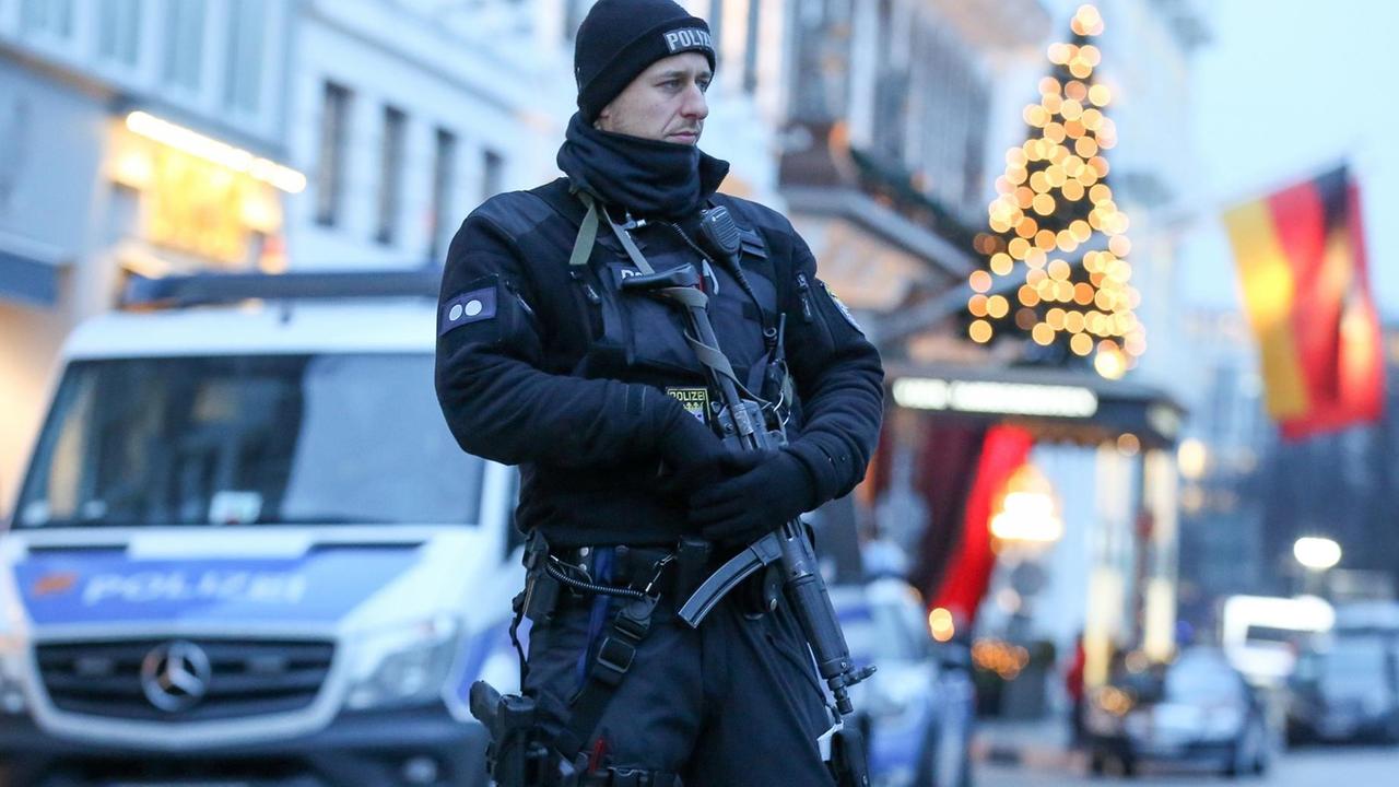 Ein Polizist mit einer Maschinenpistole steht am 07.12.2016 vor dem Hotel Vier Jahreszeiten in Hamburg, in dem während des OSZE-Treffens US-Außenminister Kerry untergebracht ist. Die Tagung des OSZE-Ministerrats am 8. und 9. Dezember beschert Hamburg einen riesigen Polizeieinsatz mit mehr als 13.000 Beamten.