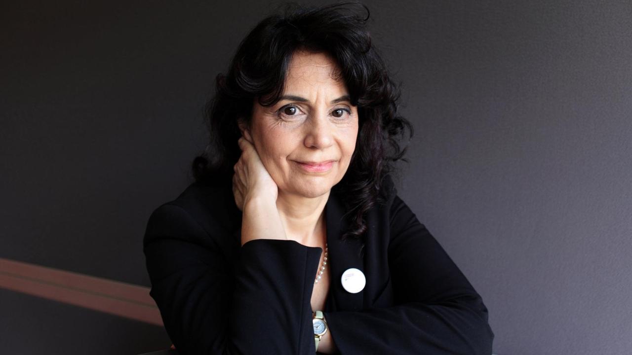 Donatella Di Cesare am runden Tisch sitzend, vor einer grauen Wand. Donatella Di Cesare am runden Tisch sitzend, vor einer grauen Wand.