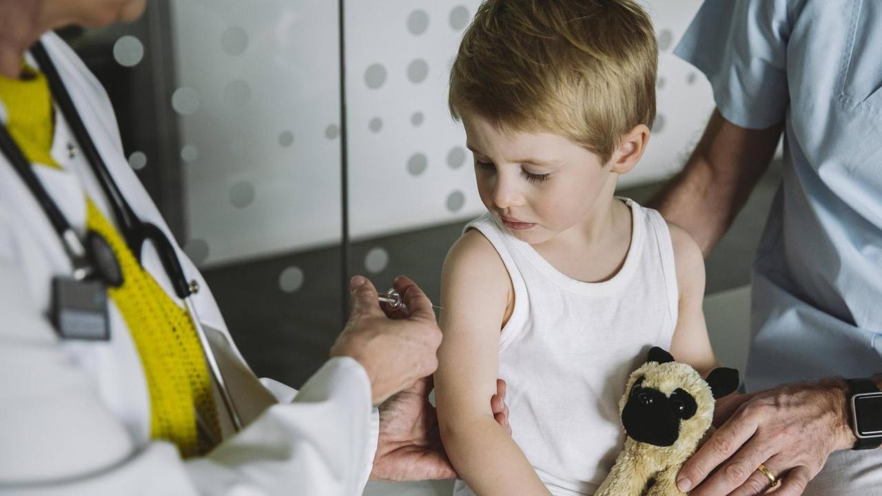 Eine Kinderärztin setzt einem Kleinkind in weißem Unterhemd eine Spritze in den Oberarm. Eine Kinderärztin setzt einem Kleinkind in weißem Unterhemd eine Spritze in den Oberarm.