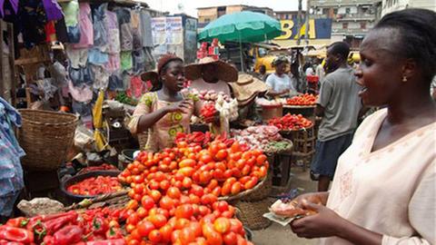 Eine junge Frau verkauft Gemüse auf dem Markt von Lagos, Nigeria.