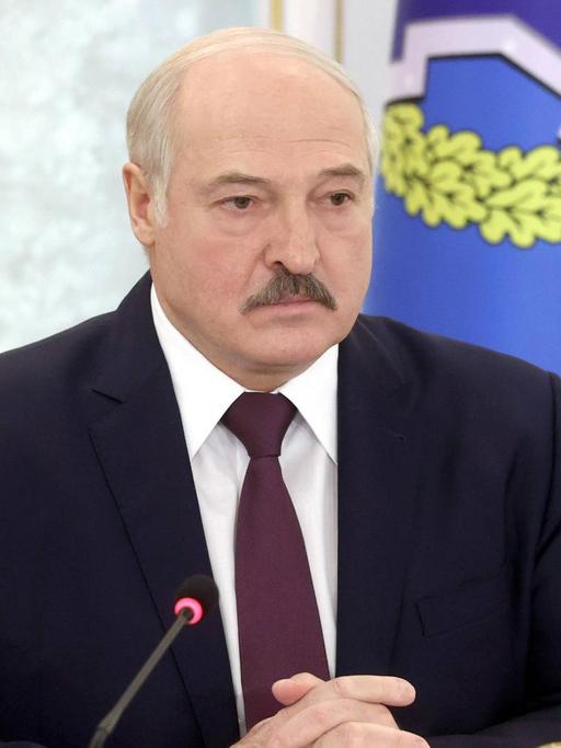 Alexander Lukaschenko sitzt vor zwei Mikrofonen.