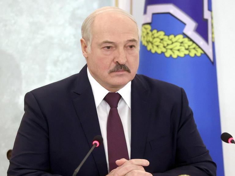 Alexander Lukaschenko sitzt vor zwei Mikrofonen.
