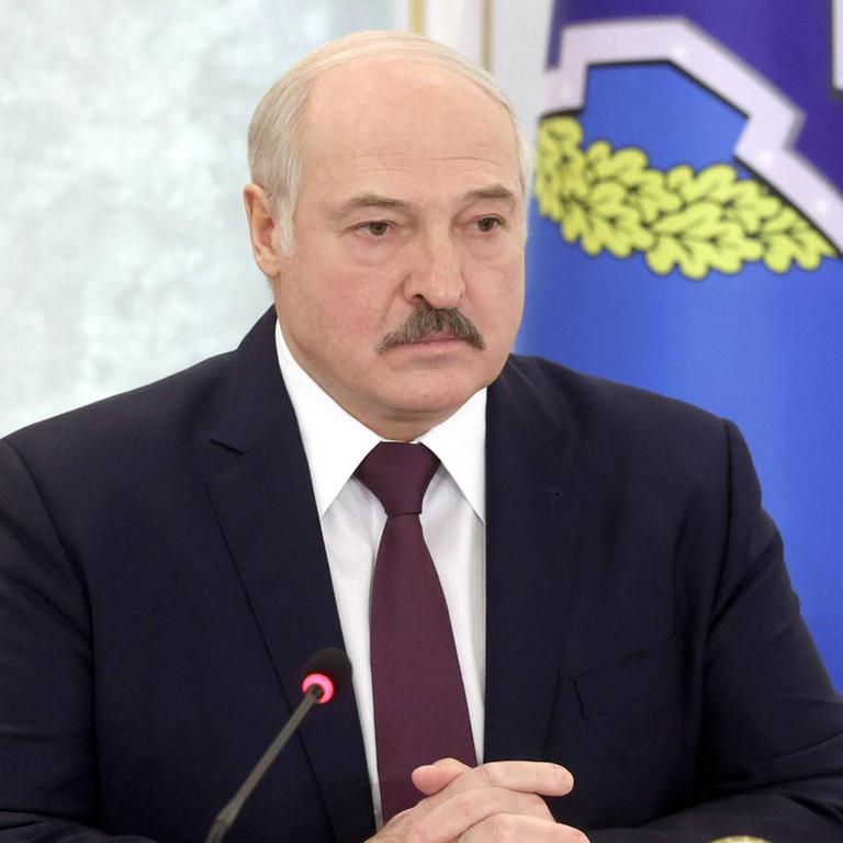Alexander Lukaschenko sitzt vor zwei Mikrofonen.