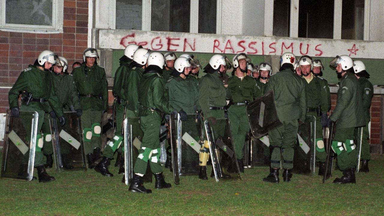 Polizisten in Kampfausrüstung haben sich in der Nacht am 27.08.1992 am inzwischen geräumten Asylbewerberheim in Rostock-Lichtenhagen vor einer von Brandspuren gezeichneten Erdgeschoss-Wohnung gesammelt. 