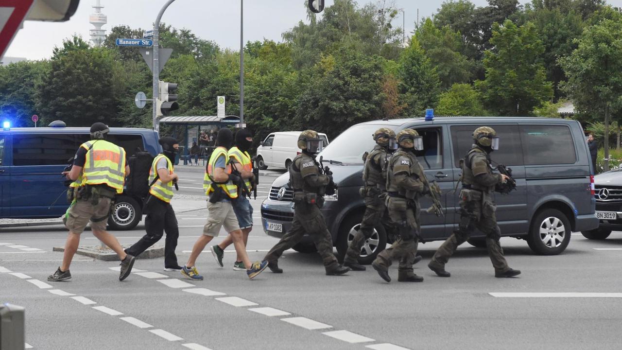 Polizisten in Spezialausrüstung kommen am 22.07.2016 in München (Bayern) zu dem Einkaufszentrum, in dem Schüsse gefallen sind. Bei Schüssen am Olympia-Einkaufszentrum in München hat es am Freitag nach Angaben der Polizei Verletzte und möglicherweise auch Tote gegeben. Polizisten in Spezialausrüstung kommen am 22.07.2016 in München (Bayern) zu dem Einkaufszentrum, in dem Schüsse gefallen sind. Bei Schüssen am Olympia-Einkaufszentrum in München hat es am Freitag nach Angaben der Polizei Verletzte und möglicherweise auch Tote gegeben.