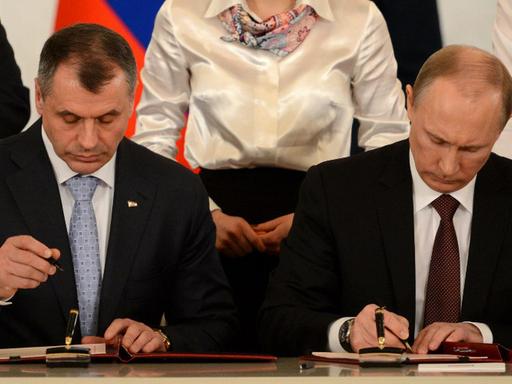 Der Sprecher der Krimparlamentes, Wladimir Konstantionov, und der russische Präsident Wladimir Putin bei der Unterzeichnung des Vertrags