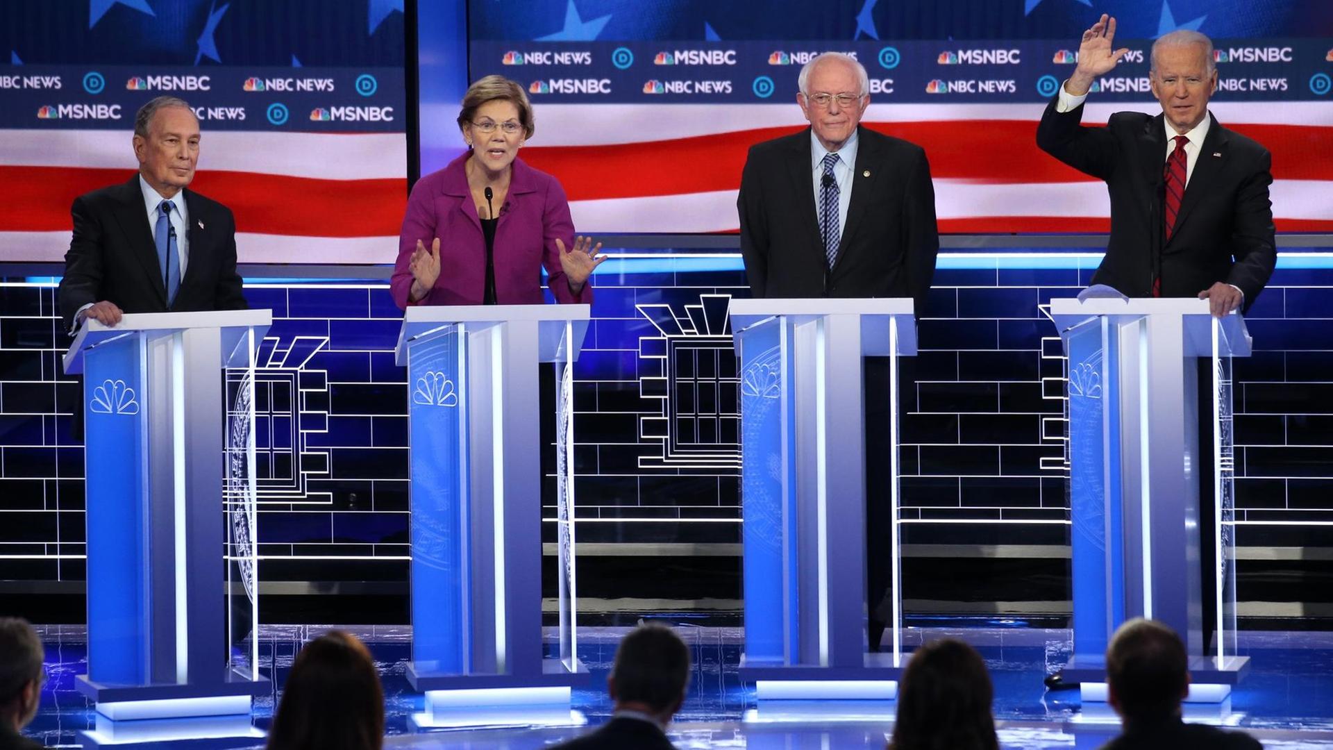 Unter anderem bewerben sich diese vier um die Kandidatur der US-Demokraten für die Präsidentschaftswahl in den USA: Michael Bloomberg, Elizabeth Warren, Bernie Sanders und Joe Biden. Sie stehen auf einer Bühne hinter vier leuchtenden Rednerpults. Unter anderem bewerben sich diese vier um die Kandidatur der US-Demokraten für die Präsidentschaftswahl in den USA: Michael Bloomberg, Elizabeth Warren, Bernie Sanders und Joe Biden. Sie stehen auf einer Bühne hinter vier leuchtenden Rednerpults.